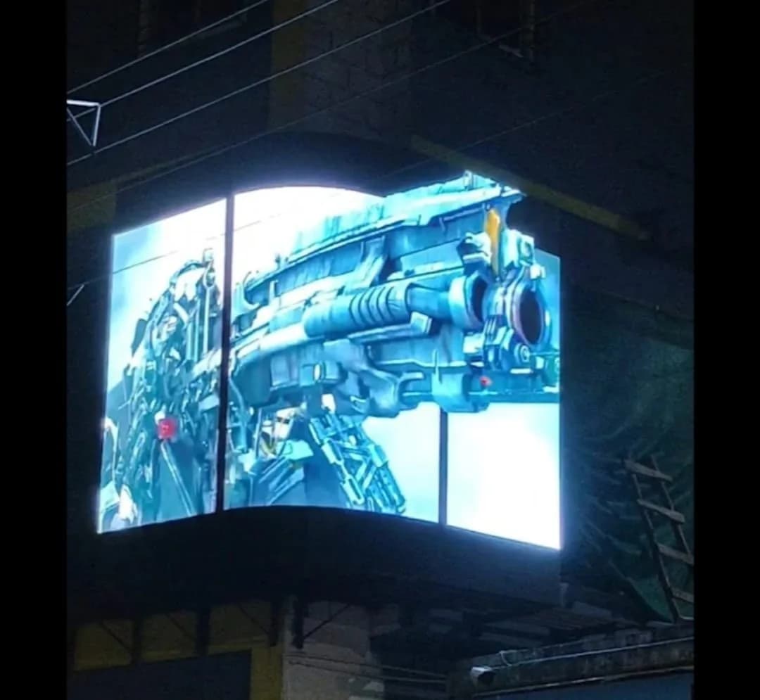 Curved outdoor LED screen wrapped around a building corner at night