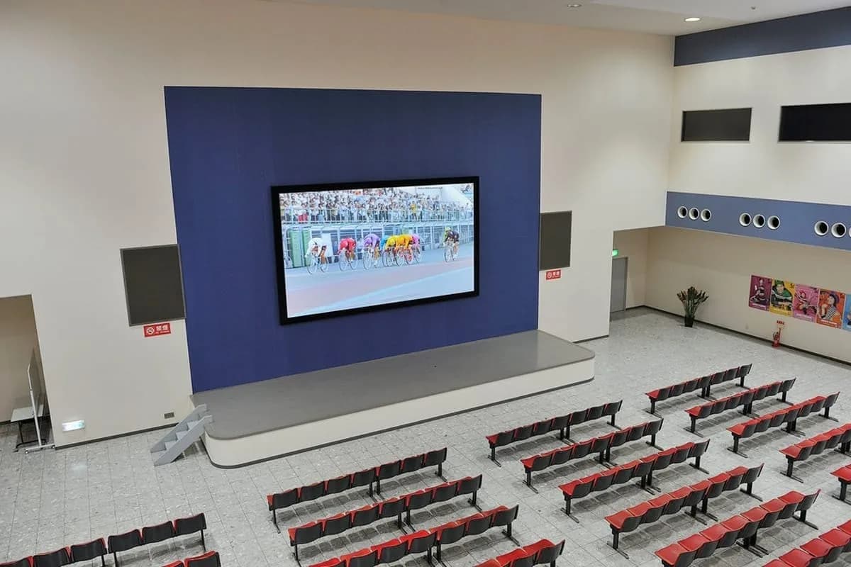 Hall with a raised stage, an LED screen and rows of seats