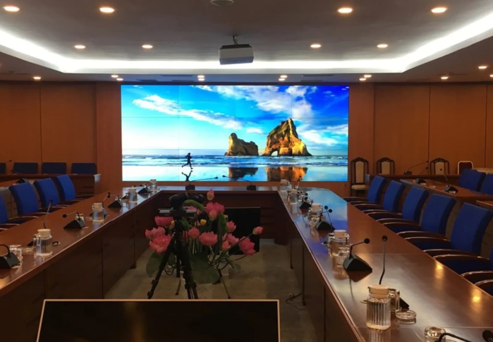 Indoor LED wall at the end of a conference room with a long table and blue chairs